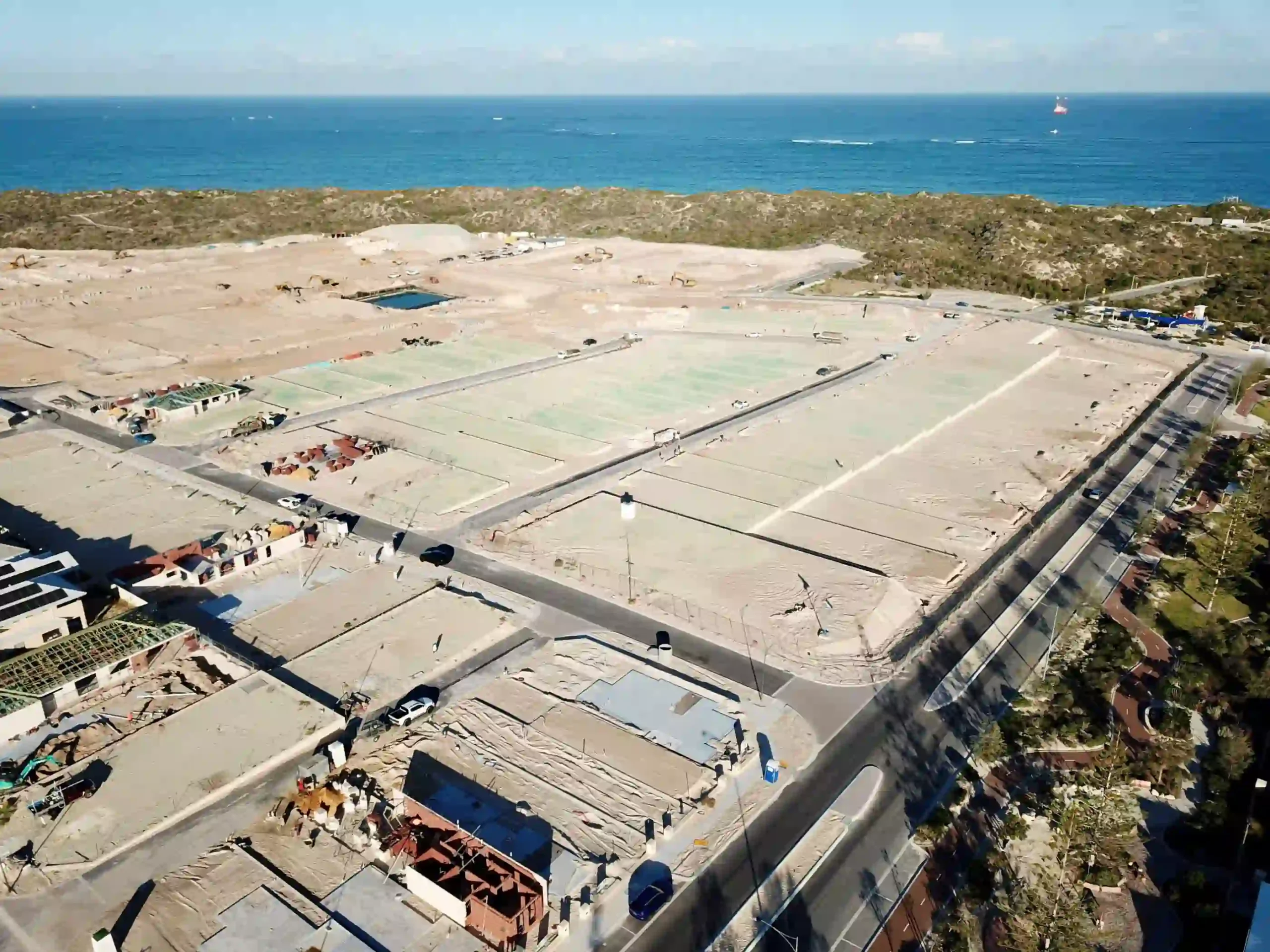Aerial view of a coastal housing development and land subdivision near the ocean.